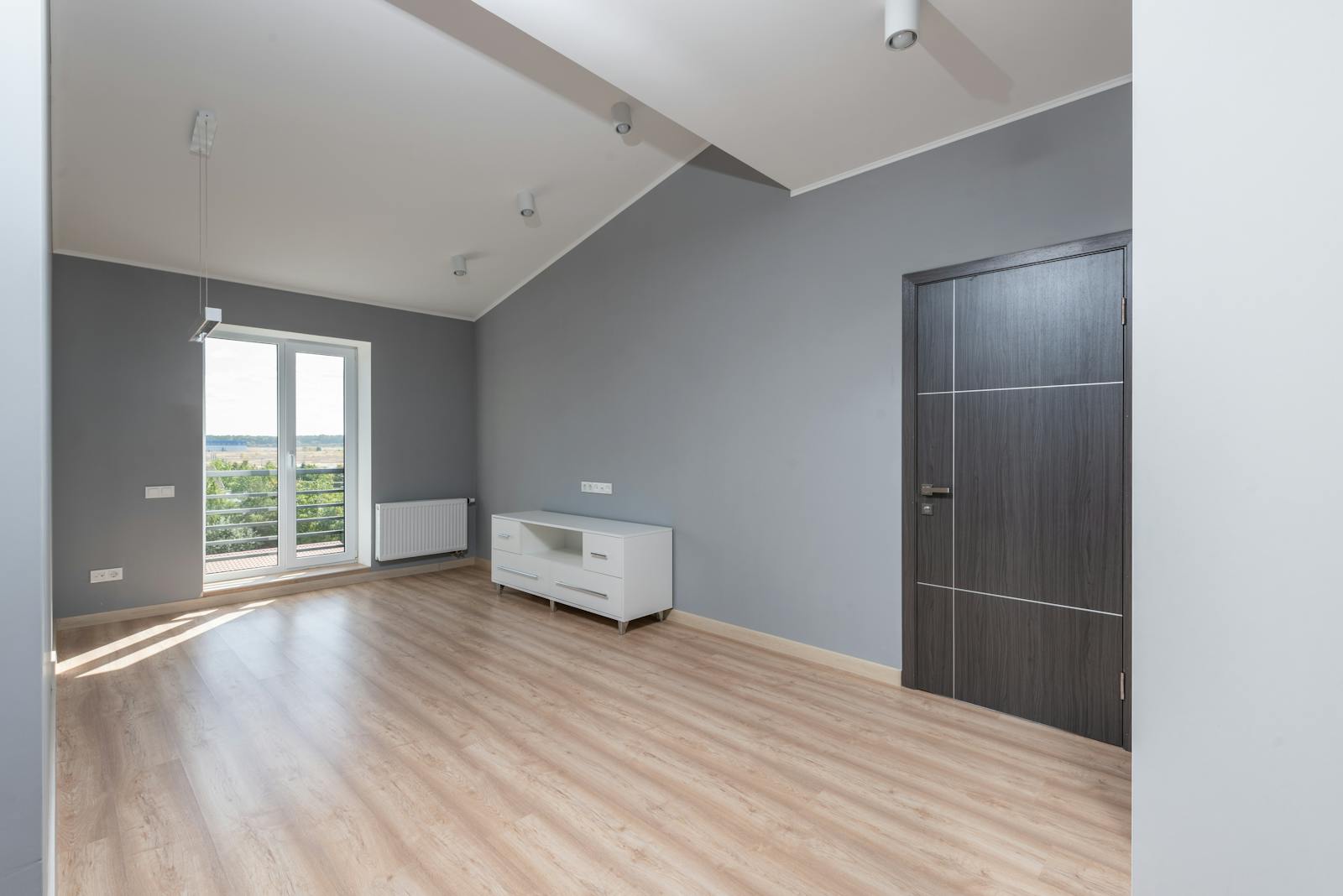 Komplett leergeräumte Wohnung mit hellem Holzboden und großem Fenster, bereit zur Übergabe.