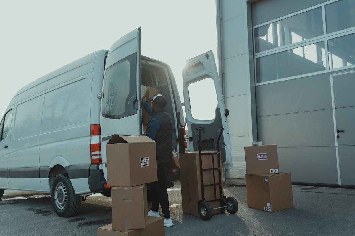 Helfer belädt einen weißen Sprinter mit Kartons für die fachgerechte Entsorgung mit Nachweis auf Wunsch.
