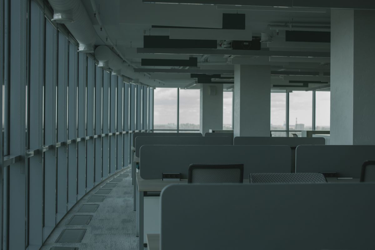 Leeres Büro mit Schreibtischreihen und Panoramafenster nach einer Gewerbe- und Geschäftsauflösung.